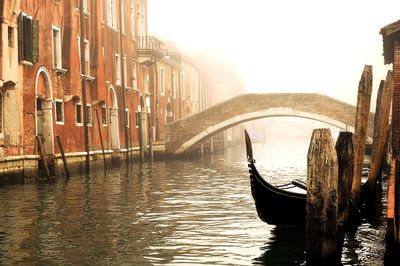 Gondola moored by wooden posts in canal