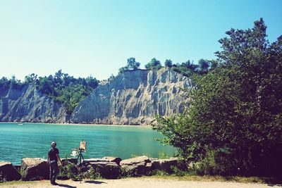 People on rock formation in sea