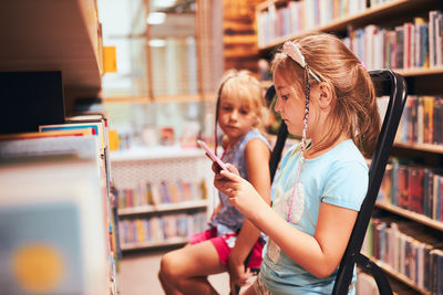 Schoolgirls looking for books in school library. students choosing books. elementary education