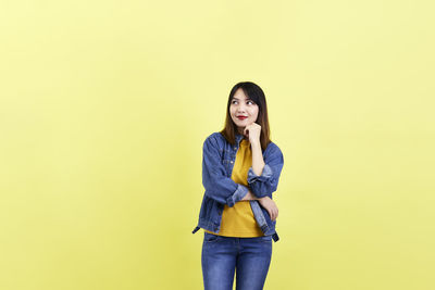 Portrait of a smiling young woman against yellow background