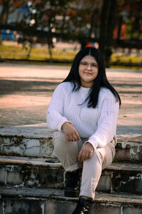 Portrait of smiling young woman sitting outdoors