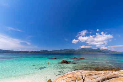 Scenic view of sea with woman against blue sky