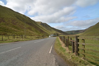 Road leading towards mountains against sky