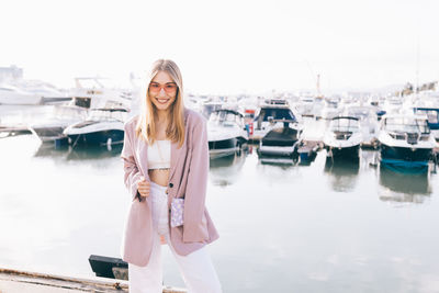 Portrait of a happy cheerful emotional traveling girl in fashionable clothes near yachts and water