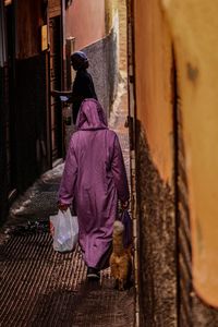 Rear view of woman walking on footpath in city