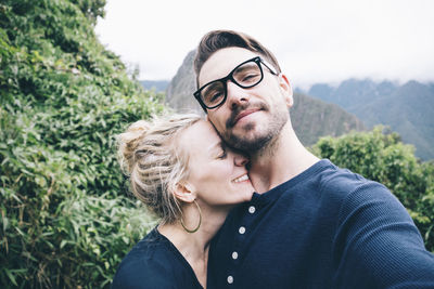 Portrait of man with girlfriend standing on mountain against sky