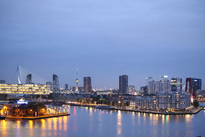 Illuminated city by river against sky at night