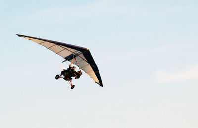 Low angle view of person hang-gliding against clear sky