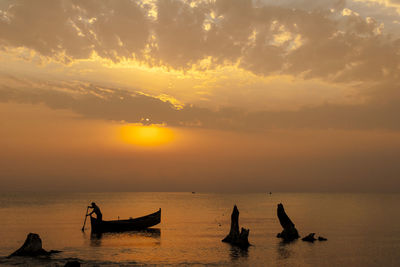 Silhouette boats in sea against sky during sunset