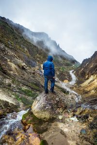 Rear view of man standing on mountain against sky