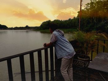 Rear view of man looking at railing against sky