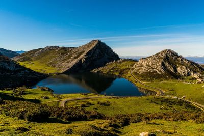 Scenic view of lake and mountains against blue sky