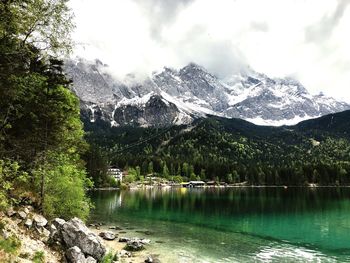 Scenic view of lake by snowcapped mountains against sky