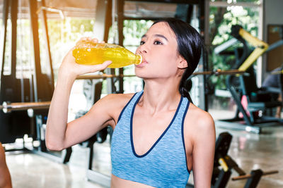 Woman having drink from bottle at gym