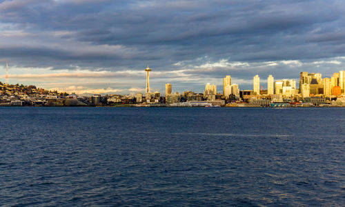 The setting sun makes a section of the city of seattle shine across elliott bay.