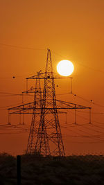 Silhouette electricity pylon against romantic sky at sunset