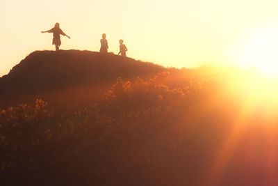 Silhouette people standing against sky during sunset