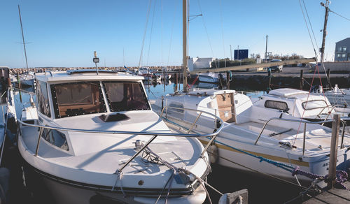 Sailboats moored at harbor against clear sky