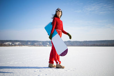 Snowboarder holding snowboard standing on mountain.