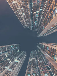 Directly below shot of modern buildings against sky at night