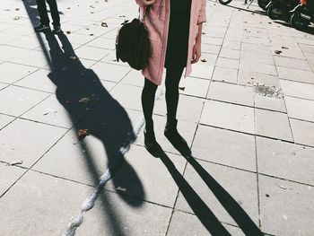 Low section of young woman standing on footpath