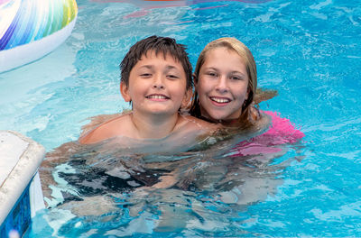 Two cousins pose in a swimming pool while on vacation