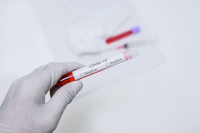 Close-up of hand holding paper over white background