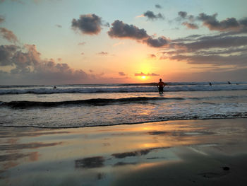 Silhouette people on beach against sky during sunset