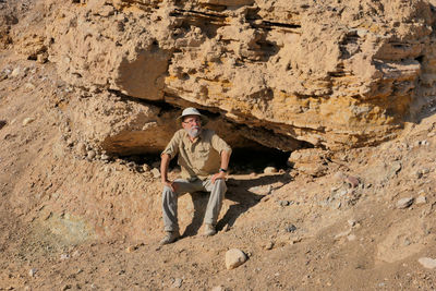 Senior man sitting on rock in the desert 