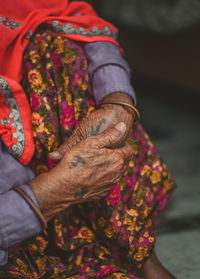 Midsection of senior woman with tattoo on hands sitting outdoors