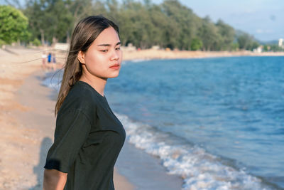 Portrait of a beautiful young woman standing on beach