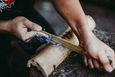 Midsection of man cutting bamboo