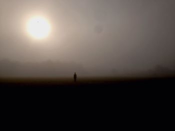 Silhouette person on field against sky during sunset