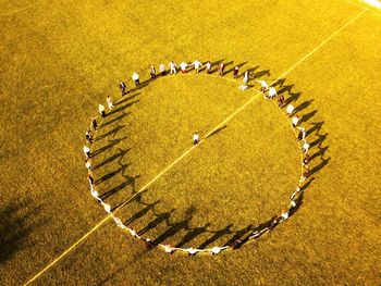 High angle view of people forming circle on field during sunny day