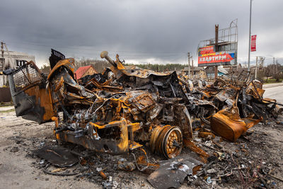 Burnt military vehicles soldiers on the bridge across the river. rusty cars. charred car parts.