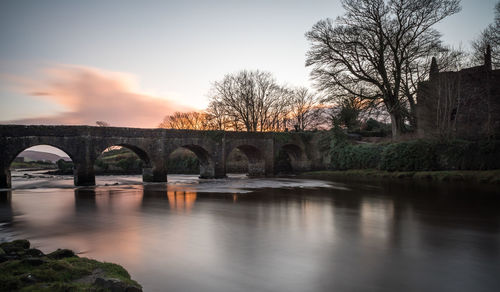 Bridge over river against sky during sunset