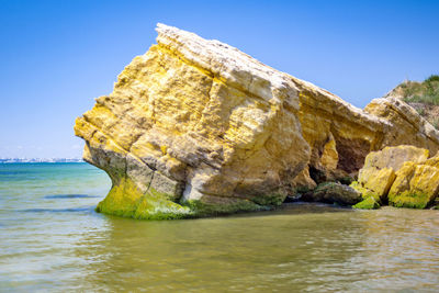 Rock formation in sea against clear sky