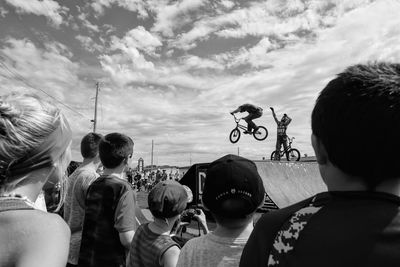 People looking at bicycles against sky