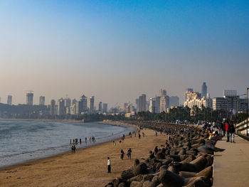 Group of people on beach against buildings in city