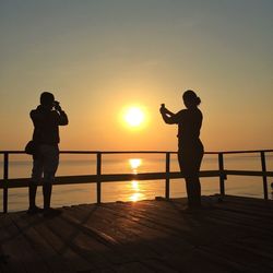 Silhouette of people standing on landscape at sunset