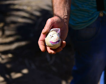 Midsection of man holding duck egg with smiley face