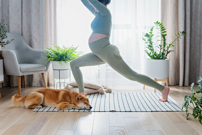 Pregnant female doing prenatal yoga at home in the brightly living room