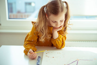 Cute girl painting while sitting at home