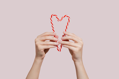 Cropped hands of woman holding heart shape against white background