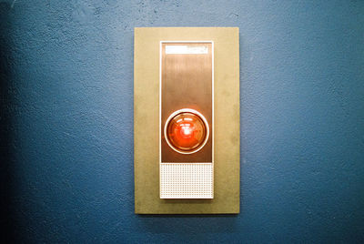 Close-up of orange push button mounted on wall