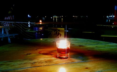 Illuminated wineglass on table at night