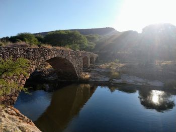 Arch bridge over river against sky