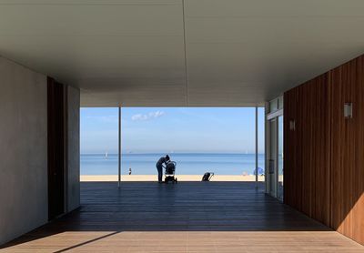 Rear view of people on sea seen through window