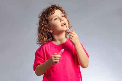 Thoughtful girl applying make-up against white background