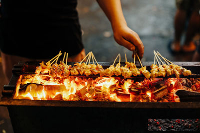 Midsection of man preparing satay on barbecue